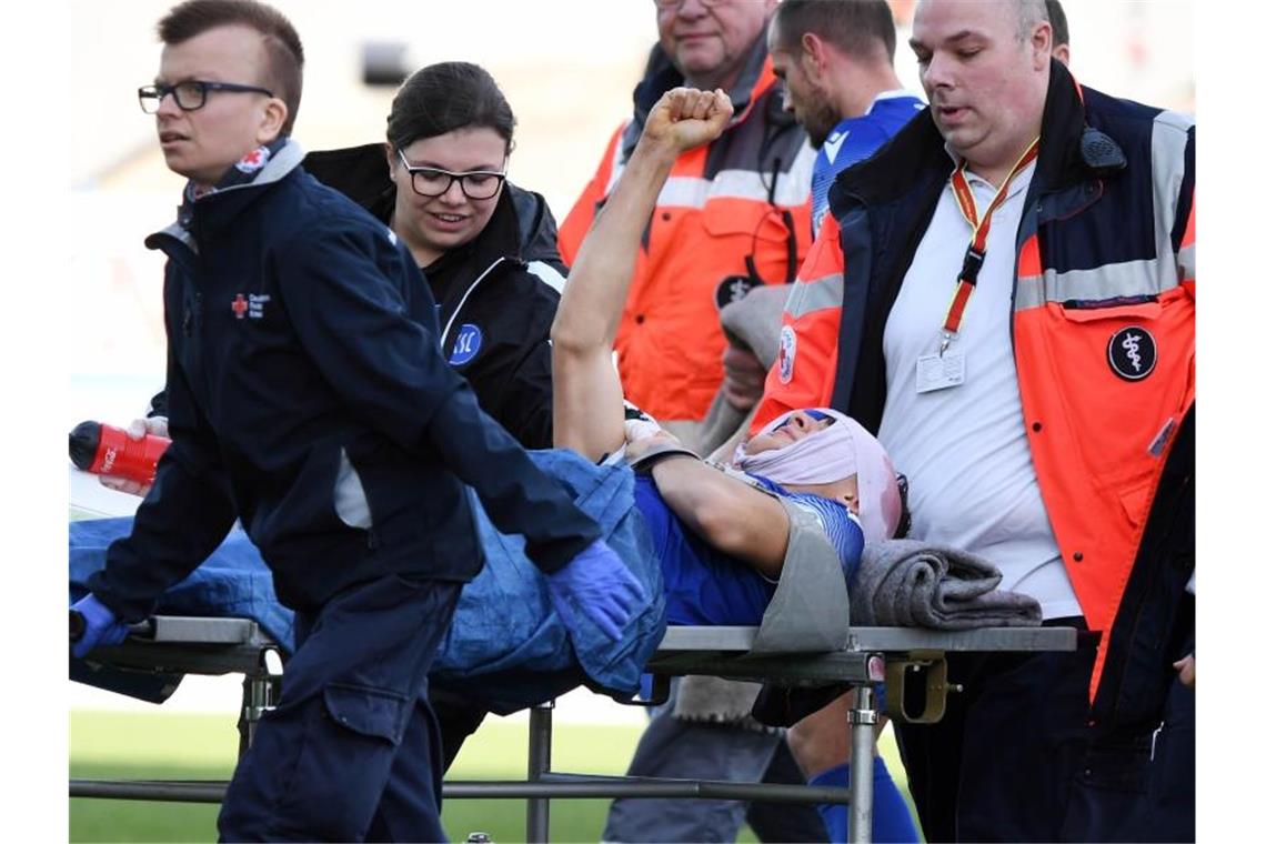 Der Fußballspieler Dirk Carlson vom Karlsruher SC wird verletzt vom Platz gebracht. Foto: Uli Deck/dpa
