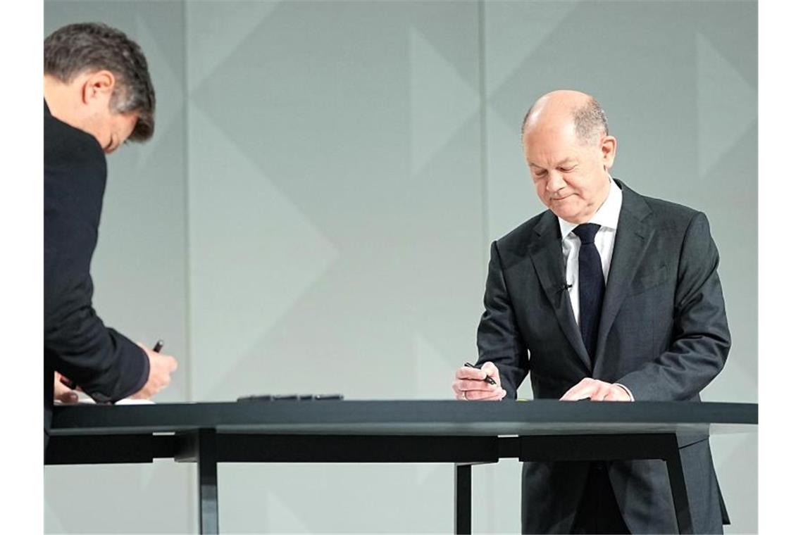 Koalitionsvertrag unterzeichnet: Ampel-Bündnis steht Der Grünen-Vorsitzende Robert Habeck (l) und der neue Kanzler Olaf Scholz (SPD) setzen ihre Unterschriften unter das Dokument. Foto: Michael Kappeler/dpa