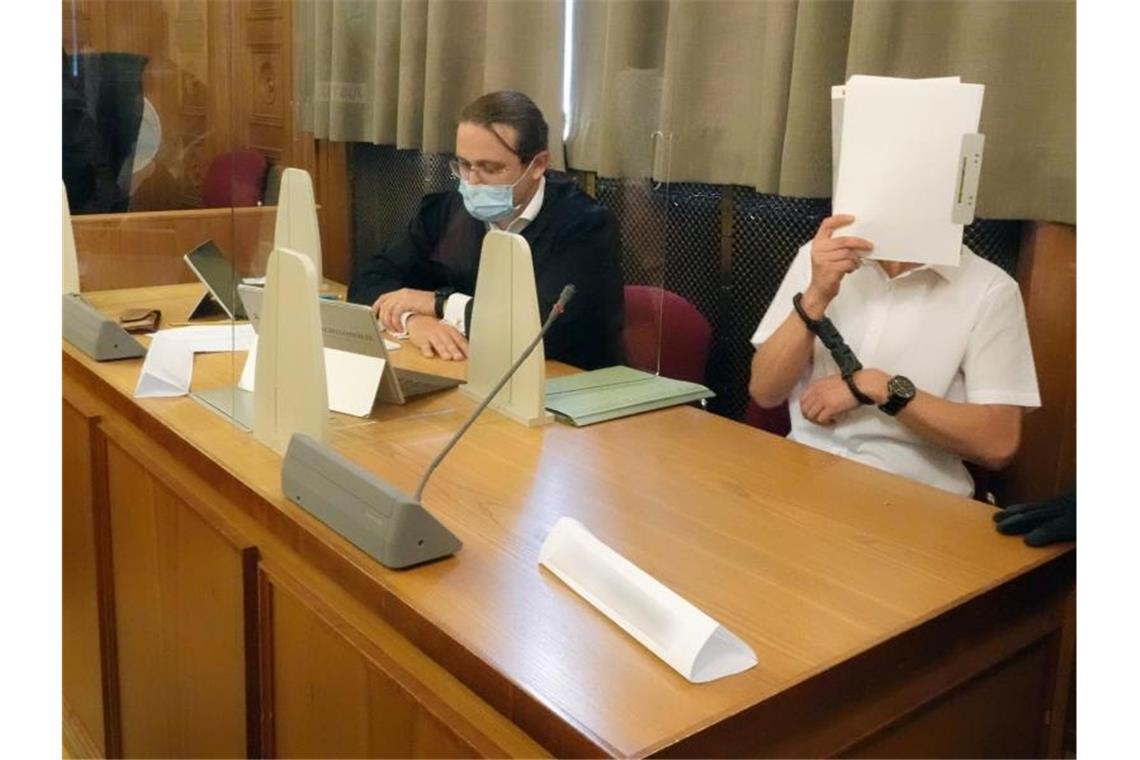 Prozess um Waffenlager: Angeklagter plante Bürgerwehr Der Hauptangeklagte (r) verdeckt sein Gesicht. Foto: Vanessa Reiber/dpa