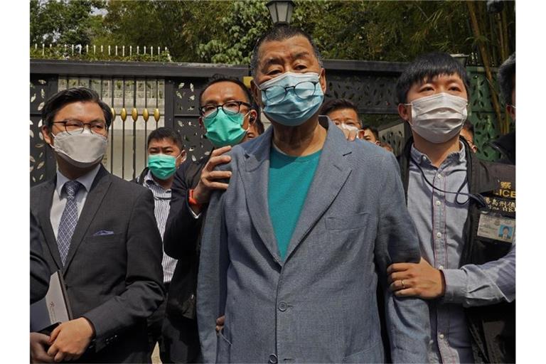Der Hongkonger Medientycoon Jimmy Lai (M), Gründer der pro-demokratischen Lokalzeitung Apple Daily, wird nach seiner Verhaftung von Polizisten eskortiert. Foto: Vincent Yu/AP/dpa