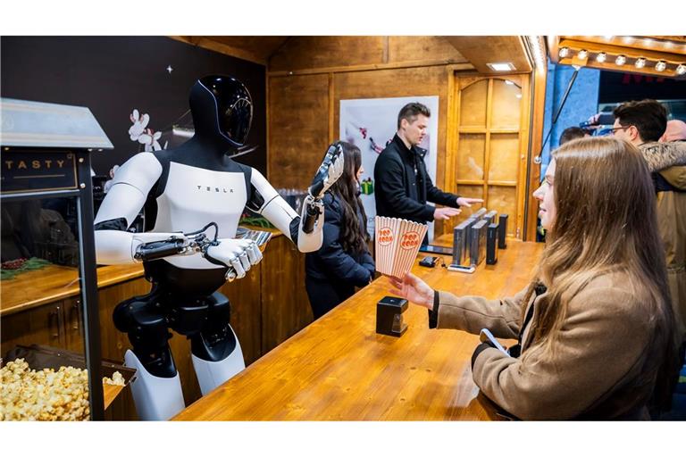 Der humanoide Roboter "Optimus" von Tesla verteilt bei seiner Vorstellung in der Mall of Berlin Popcorn an eine Besucherin.