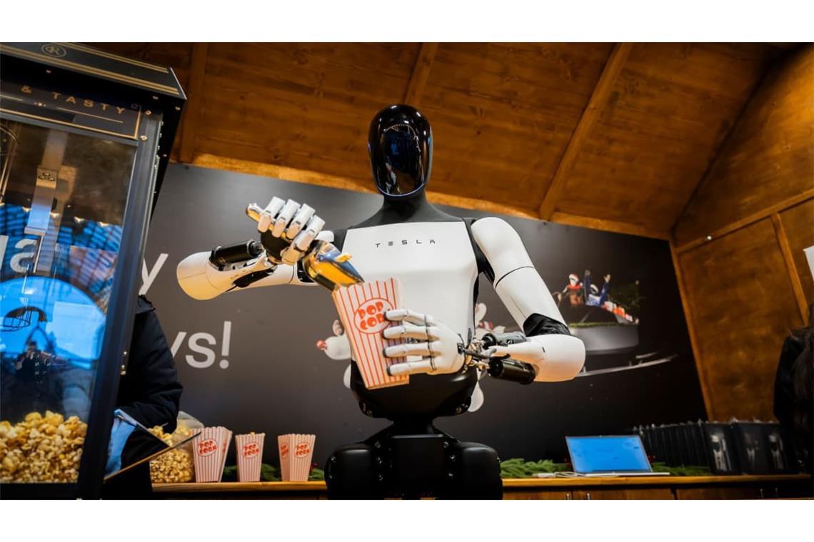 Der humanoide Roboter „Optimus“ von Tesla verteilt bei seiner Vorstellung in der Mall of Berlin Popcorn an einem Weihnachtsmarktstand.