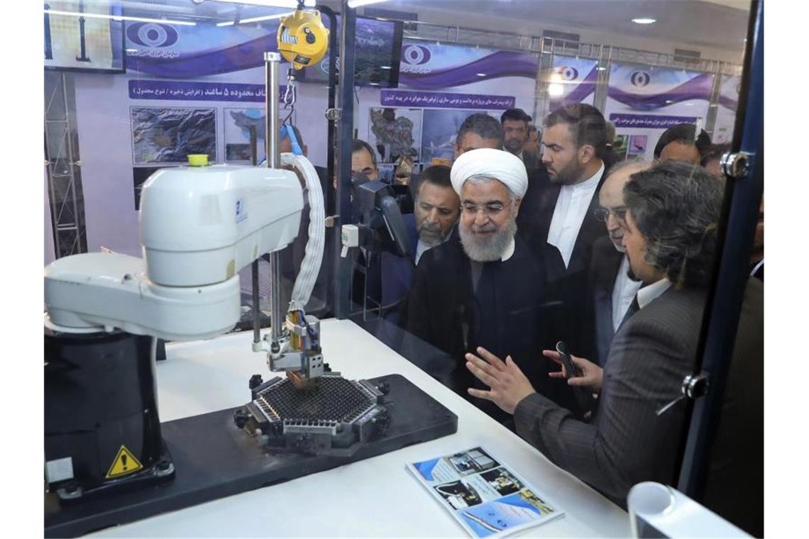 Ruhani: Iran will nicht komplett aus Atomabkommen aussteigen Der iranische Präsident Hassan Ruhani (M.) lässt sich neue Entwicklungen in der Atomenergie im Rahmen des „Nationalen Atomtags“ erklären. Foto: Uncredited/Iranian Presidency Office/AP/dpa