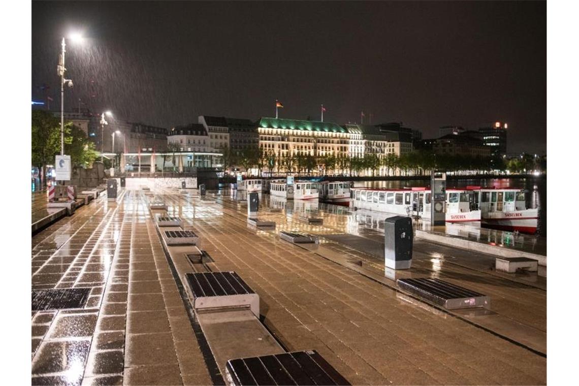 Der Norden lockert - Ausgangsbeschränkung in Hamburg fällt Der Jungfernstieg ist kurz nach 0 Uhr bei Regen menschenleer. Seit Mitternacht ist die wegen der Coronapandemie geltende Ausgangssperre aufgehoben. Foto: Daniel Bockwoldt/dpa