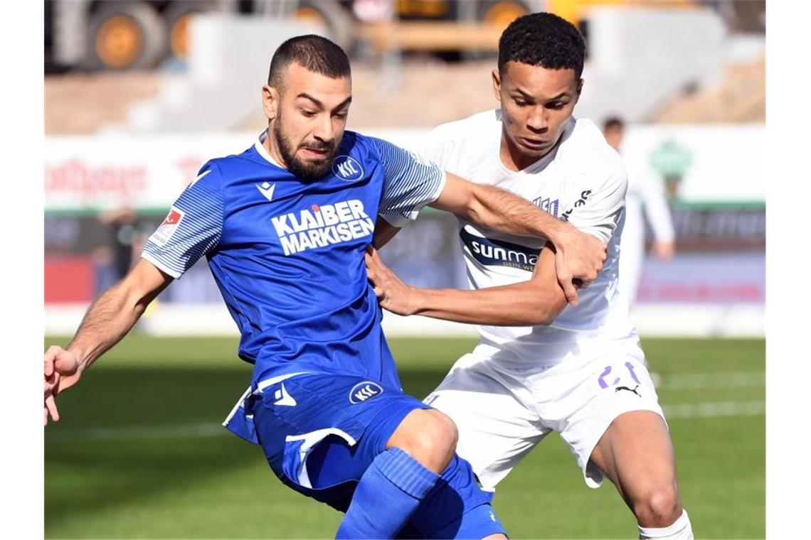 Der Karlsruher Burak Camoglu (l) und der Osnabrücker Felix Agu kämpfen um den Ball. Foto: Uli Deck/dpa