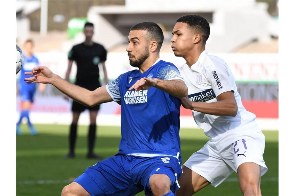 Der Karlsruher Burak Camoglu (l) versucht den Ball vor dem Osnabrücker Felix Agu abzuschirmen. Foto: Uli Deck/dpa