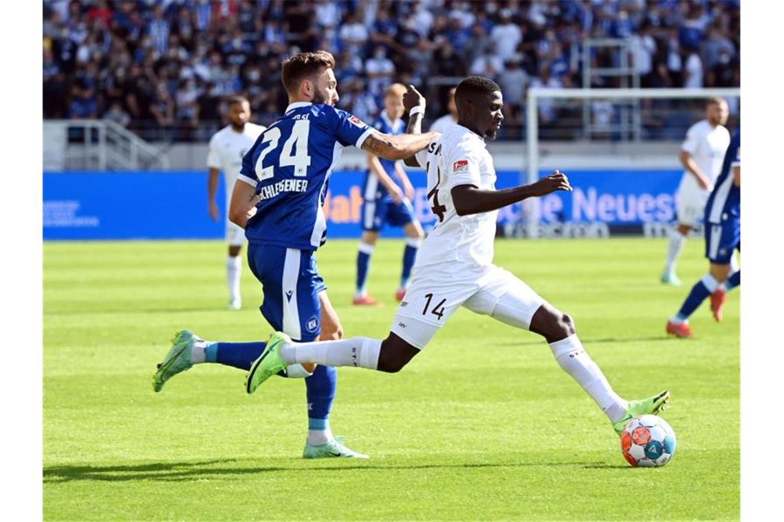 Der Karlsruher Fabian Schleusener (l) und St. Paulis Afeez Aremu kämpfen um den Ball. Foto: Uli Deck/dpa