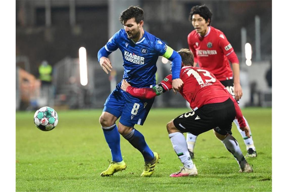 Der Karlsruher Jerôme Gondorf (l) und der Hannoveraner Dominik Kaiser kämpfen um den Ball. Foto: Uli Deck/dpa/Archiv