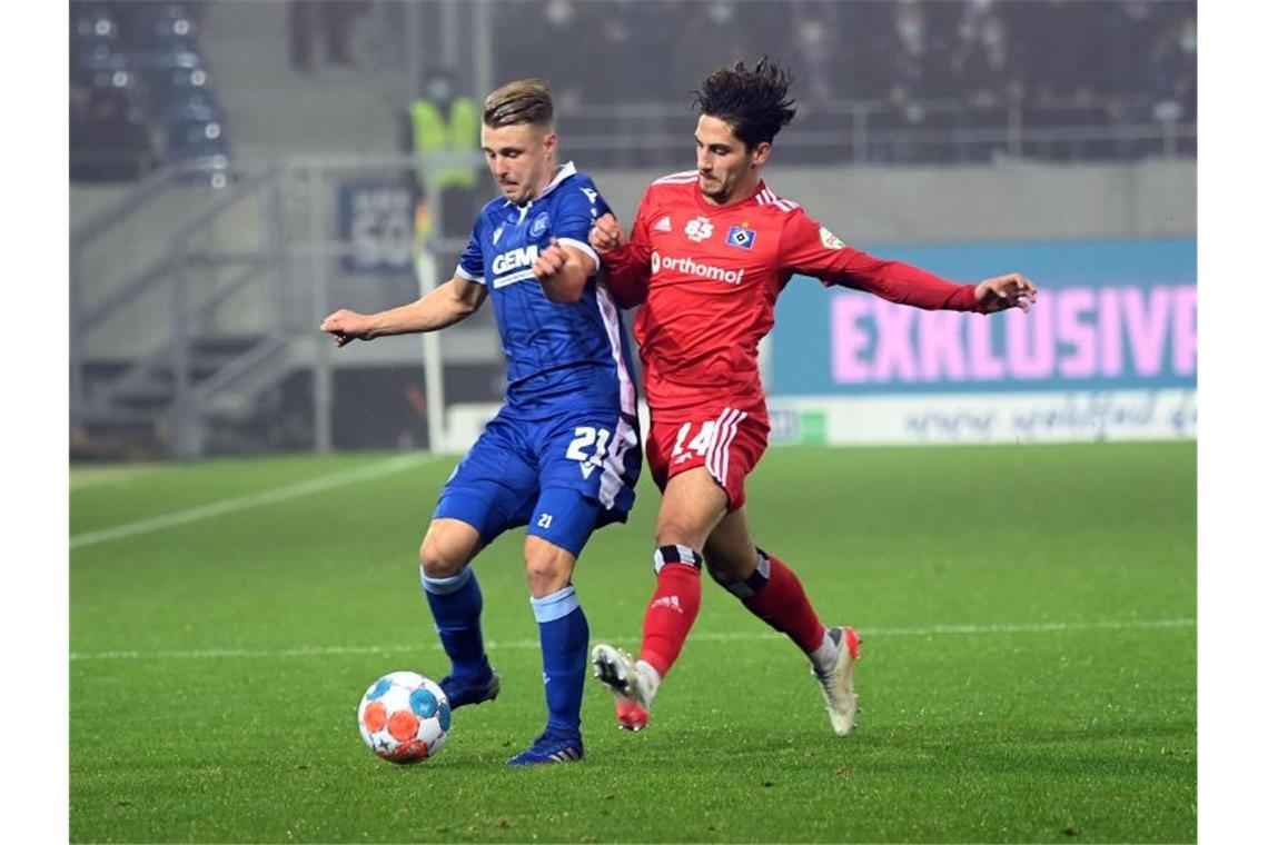 Der Karlsruher Marco Thiede (l) und der Hamburger Ludovit Reis kämpfen um den Ball. Foto: Uli Deck/dpa/Archivbild