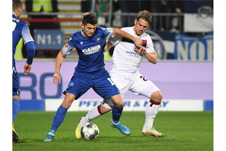 Der Karlsruher Marvin Wanitzek (l.) und der Nürnberger Oliver Sorg kämpfen um den Ball. Foto: Uli Deck/dpa