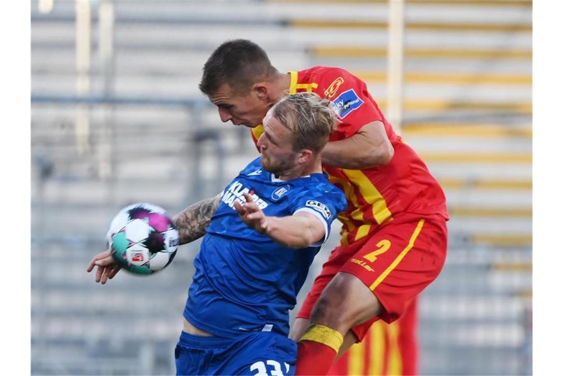 Der Karlsruher Philipp Hofmann (l) und Uwe Hünemeier vom KSC kämpfen um den Ball. Foto: Uli Deck/dpa