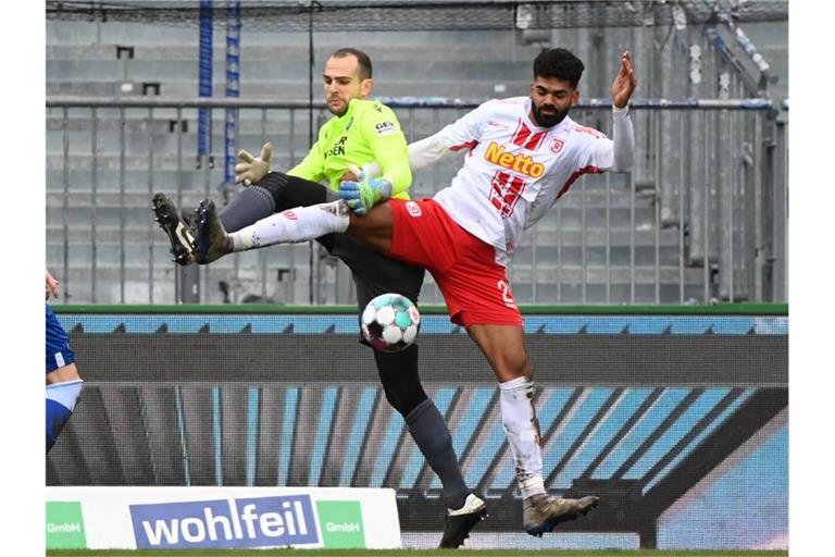 Der Karlsruher Torhüter Marius Gersbeck (l) und der Regensburger Andre Becker kämpfen um den Ball. Foto: Uli Deck/dpa