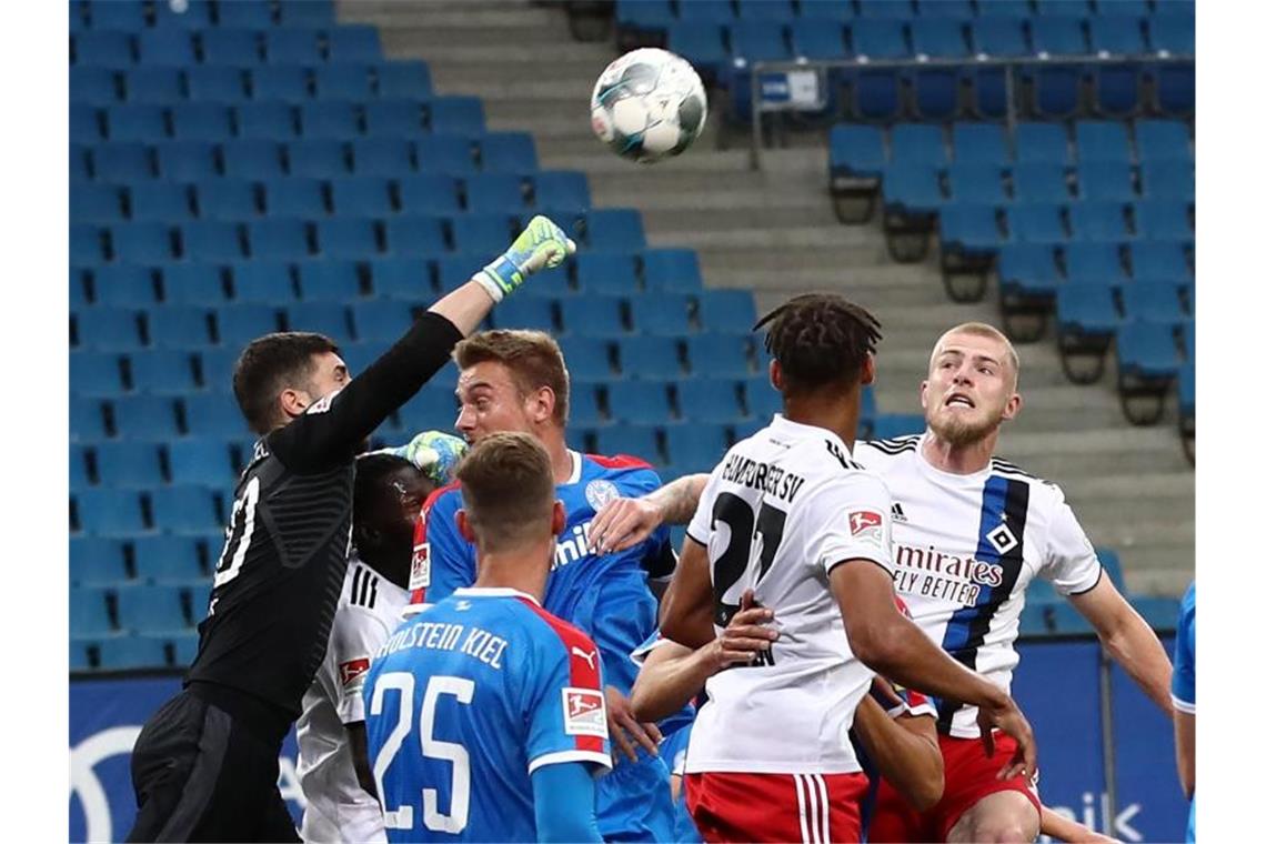 Der Kieler Torwart Ioannis Gelios (l-r) faustet den Ball vor seinen Teamkameraden Phil Neumann, Hauke Wahl und den Hamburgern Josha Vagnoman und Rick van Drongelen weg. Foto: Christian Charisius/dpa-Pool/dpa