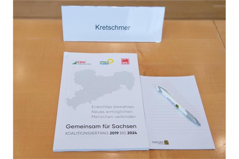 Der Koalitionsvertrag auf dem Platz von Sachsens Ministerpräsident Kretschmer im Landtag. Foto: Sebastian Kahnert/dpa-Zentralbild/dpa