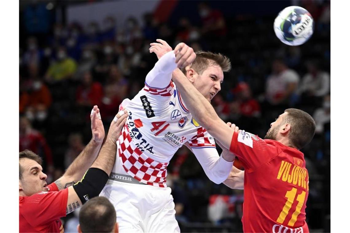 Norwegen mit Kantersieg vor Duell mit deutschen Handballern Der Kroate Tin Lucin (M) kann sich am Wurfkreis gegen zwei Spieler Montenegros durchsetzen. Foto: Tamas Kovacs/MTI/dpa