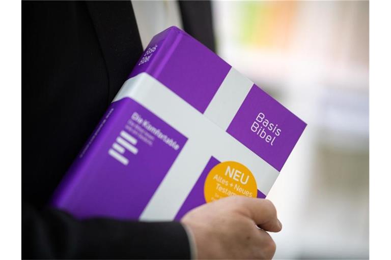 Der Landesbischof der Evangelischen Landeskirche in Württemberg hält eine Ausgabe der Basisbibel in der Hand. Foto: Sebastian Gollnow/dpa