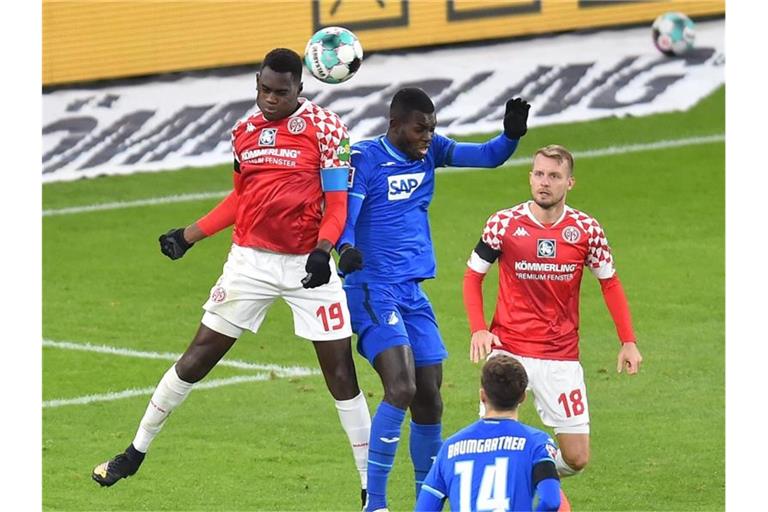 Der Mainzer Moussa Niakhate (l) im Kopfballduell mit Hoffenheims Ihlas Bebou. Foto: Torsten Silz/dpa
