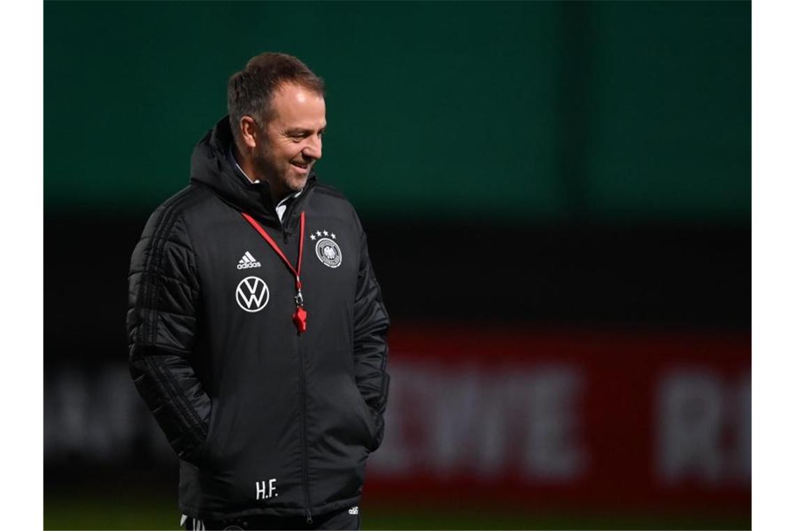 DFB-Auswahl: Flick-Pressekonferenz und Abschlusstraining Der Mann mit der roten Trillerpfeife: Bundestrainer Hansi Flick steht lächelnd auf dem Platz. Foto: Swen Pförtner/dpa