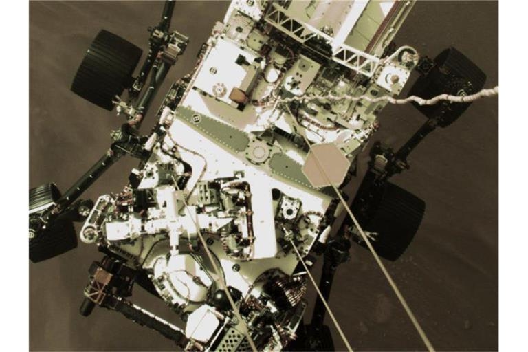 Der Mars-Rover "Perseverance" senkt sich während der Landung auf die Marsoberfläche ab. Foto: -/AP/dpa