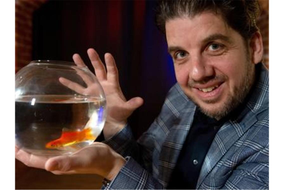 Der Mental-Magier Christoph Kuch aus Nürnberg hält ein Glas mit einem Goldfisch in der Hand. Foto: Timm Schamberger/dpa/Archivbild