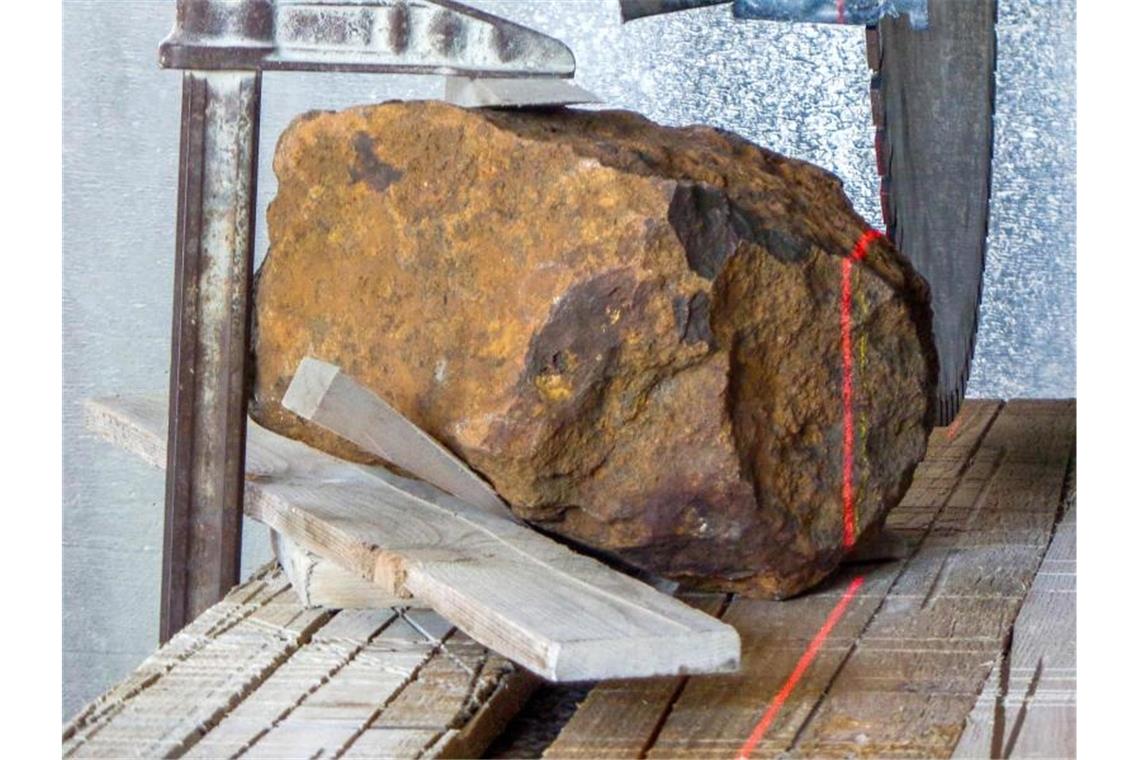 Der Meteorit liegt auf einer Werkbank. Foto: Gabriele Heinlein/Deutsches Zentrum für Luft- und Raumfahrt/dpa