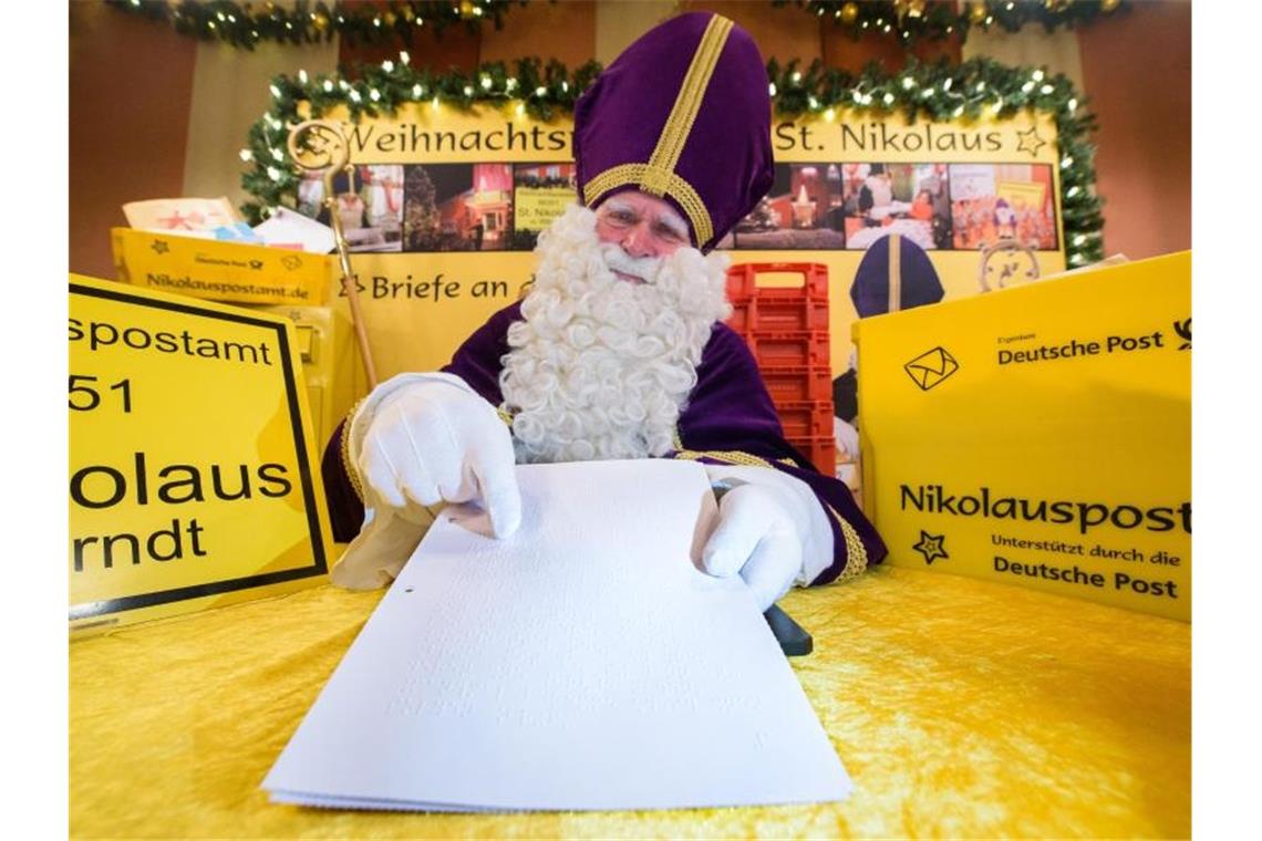 Der Nikolaus hält im Nikolauspostamt einen Brief in der Hand. Foto: Oliver Dietze/dpa