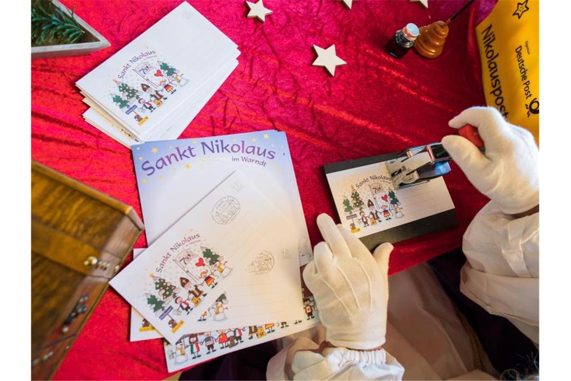 Der Nikolaus stempelt in der Nikolaushütte einen Brief ab. Foto: Oliver Dietze/dpa