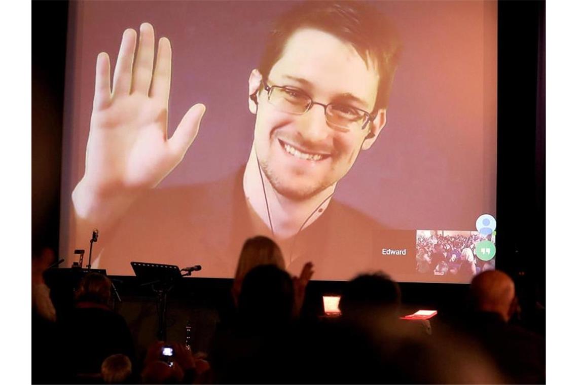 Der NSA-Enthüller Edward Snowden winkt während einer Videoschalte dem Publikum zu. Der US-Whistleblower Edward Snowden ist Vater geworden. Foto: Wolfgang Kumm/dpa