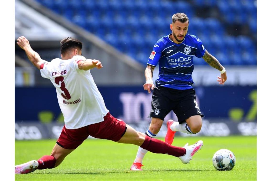 Der Nürnberger Konstantinos Mavropanos (l) grätscht in den Lauf von Arminia-Spieler Jonathan Clauss. Foto: Stuart Franklin/getty/Pool/dpa