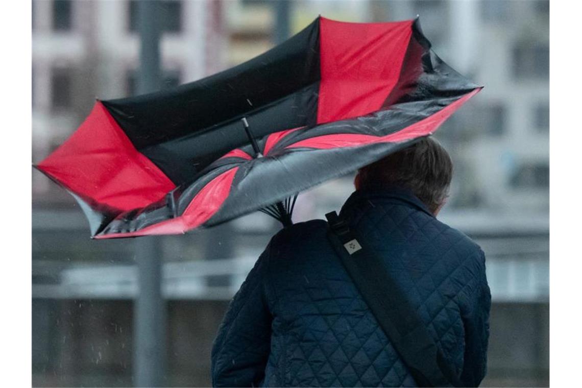 Der Regenschirm eines Spaziergängers ist wegen einer Windböe umgeklappt. Foto: Bernd Thissen/dpa/Archivbild