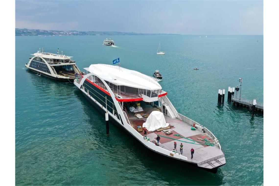 Der Rohbau einer neuen Fähre wird von einer anderen Fähre auf dem Bodensee in den Fährhafen bugsiert. Foto: Felix Kästle/dpa