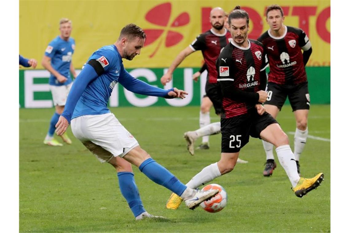 Der Rostocker John Verhoek (l) schießt den Ball Richtung Ingolstädter Tor. Foto: Bernd Wüstneck/dpa-Zentralbild/dpa