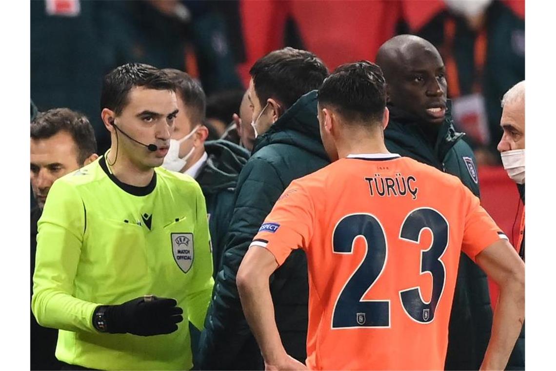 Rassismus: Partie zwischen PSG und Basaksehir unterbrochen Der rumänische Schiedsrichter Ovidiu Hategan (l) diskutiert mit Verantwortlichen und Spielern von Istanbul Basaksehir und Paris Saint-Germain. Foto: Franck Fife/AFP/dpa