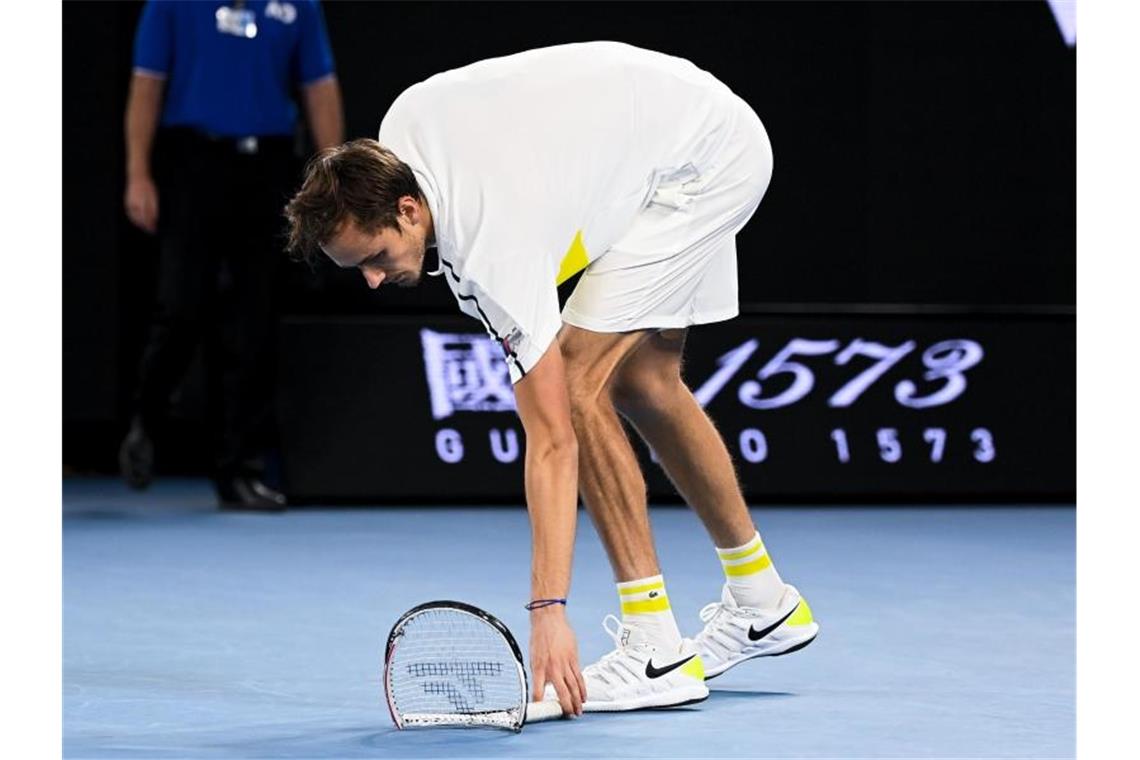Djokovic gewinnt zum neunten Mal die Australian Open Der Russe Daniil Medwedew hebt seinen zertrümmerten Schläger auf. Foto: Dave Hunt/AAP/dpa