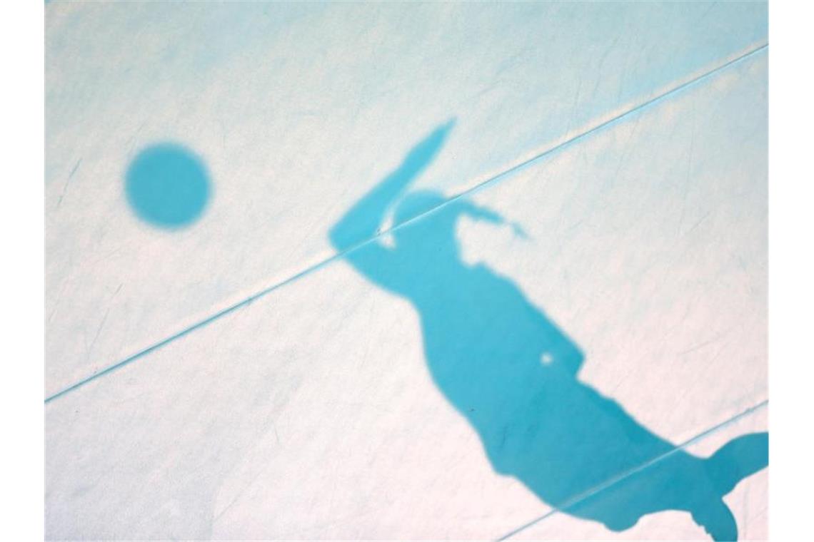 Der Schatten einer aufschlagenden Spielerin ist auf dem Hallenboden zu sehen. Foto: Friso Gentsch/dpa/Archivbild