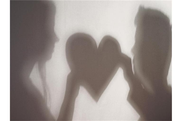 Der Schatten einer Frau und eines Mannes, die gemeinsam ein Herz halten, ist an eine Wand geworfen. Foto: Jan-Philipp Strobel/dpa/Symbolbild
