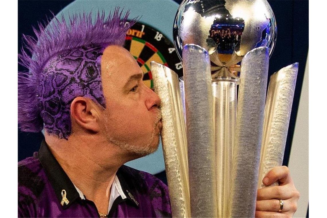 Der schottische Dartspieler Peter Wright herzt nach seinem Sieg die Sid-Waddell-Trophäe. Foto: Steven Paston/PA Wire/dpa