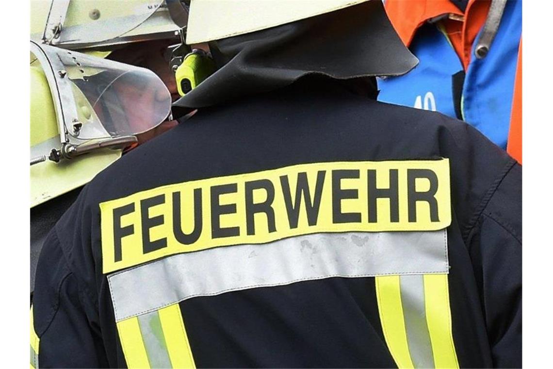 Der Schriftzug Feuerwehr steht an der Jacke eines Feuerwehrmannes. Foto: picture alliance / dpa/Illustration