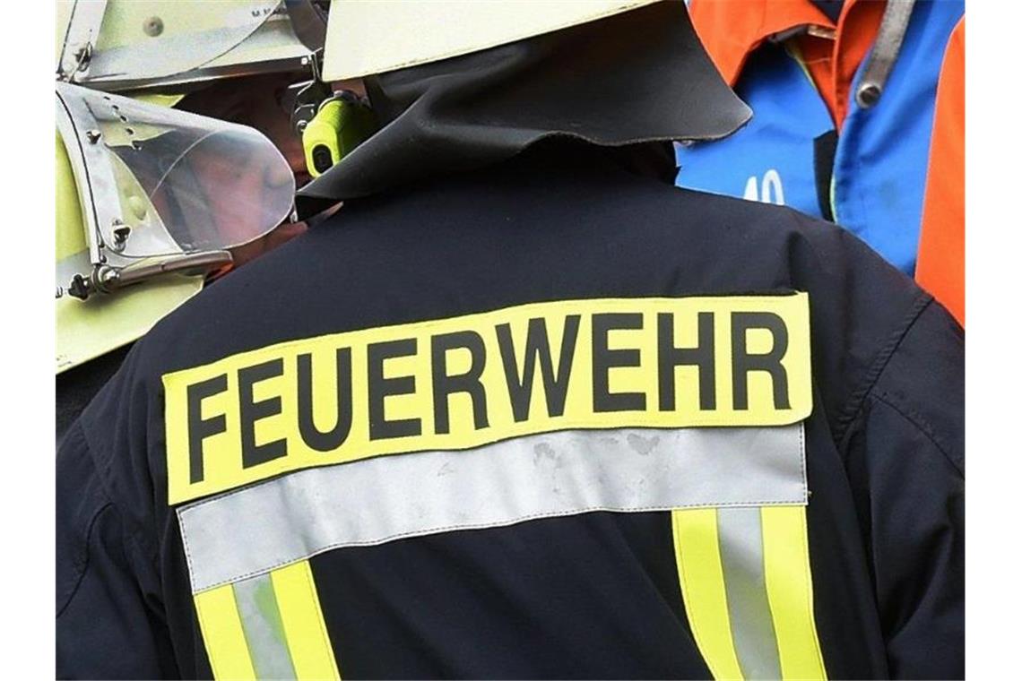 Der Schriftzug Feuerwehr steht an der Jacke eines Feuerwehrmannes. Foto: picture alliance / dpa/Illustration