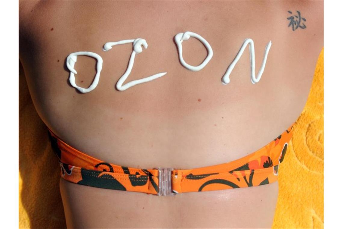 Der Schriftzug „Ozon“ aus Sonnencreme auf dem Rücken einer jungen Frau. Foto: Caroline Seidel/Archivbild