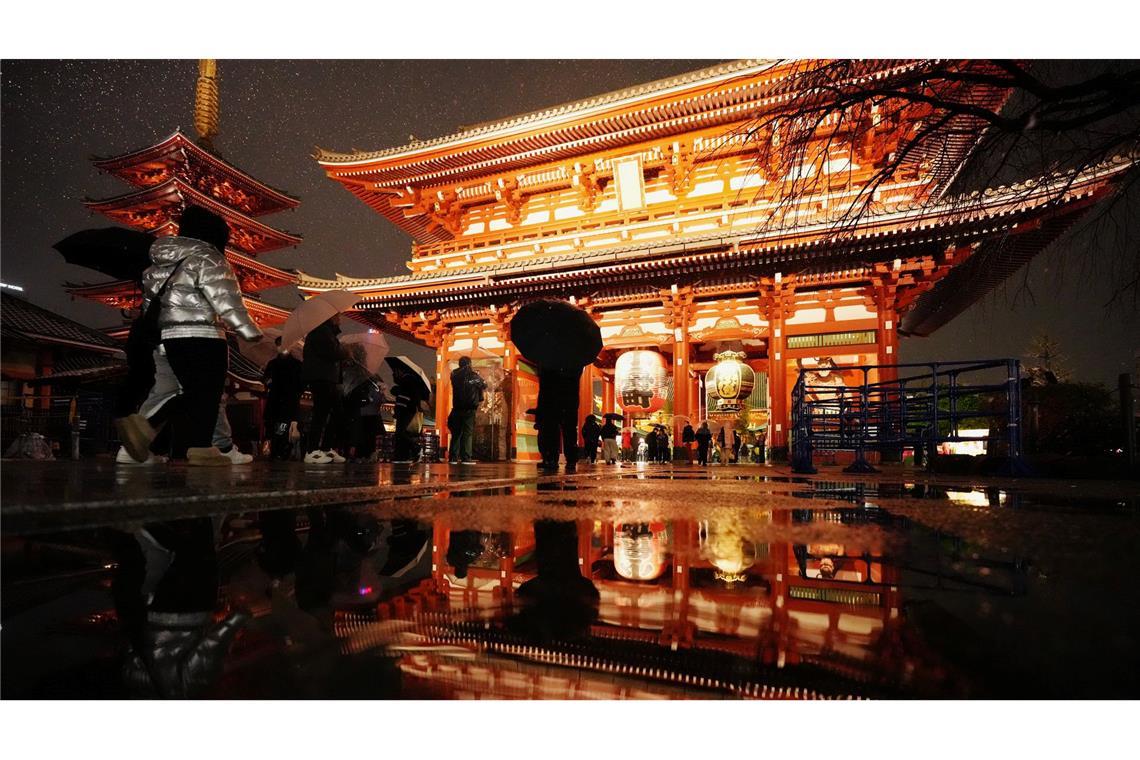 Der Sensoji-Tempel spiegelt sich in einer Pfütze, als Menschen zum Neujahrsgebet in Tokio ankommen.