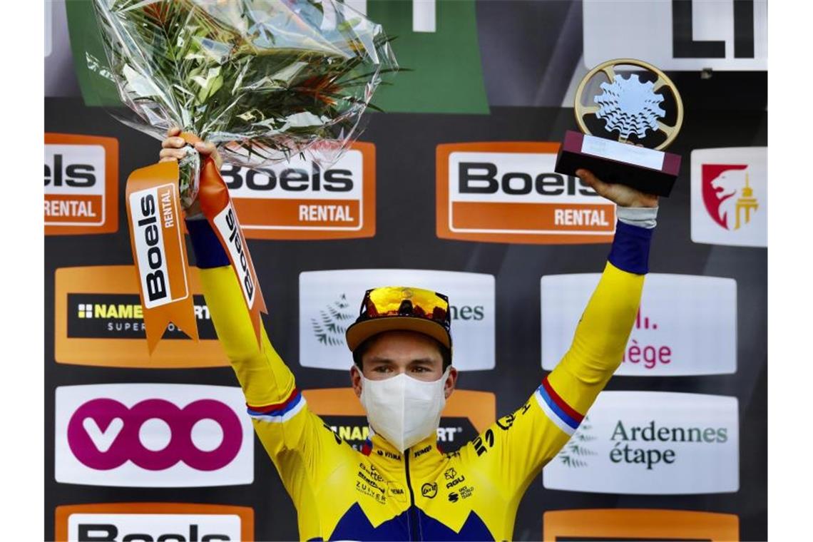 Der Slowene Primoz Roglic vom Team Jumbo jubelt mit Mund-Nasen-Schutz und Pokal bei der Siegerehrung auf dem Podium. Foto: Olivier Matthys/AP/dpa