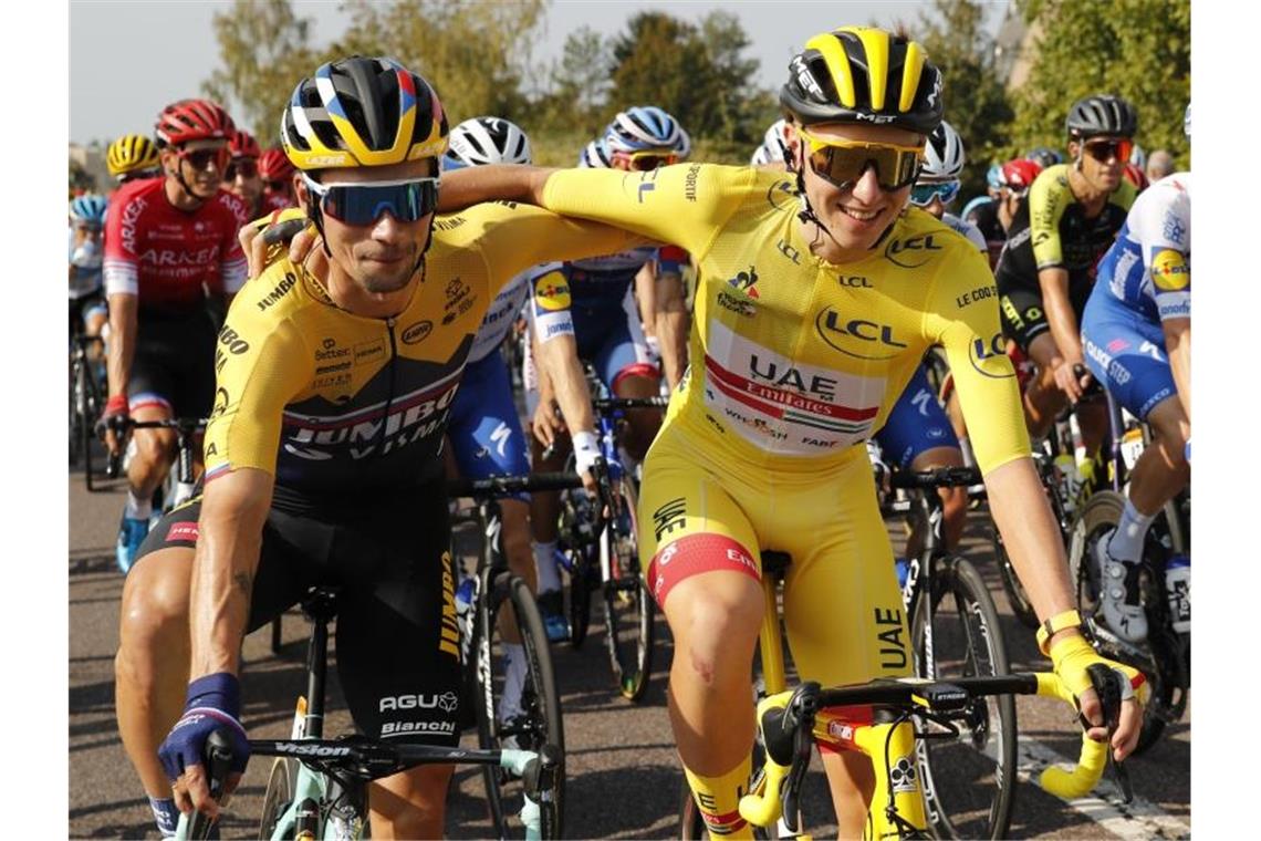 Der Slowene Tadej Pogacar (r) vom UAE Team Emirates, der das gelbe Trikot des Gesamtführenden trägt, umarmt seinen Landsmann Primoz Roglic vom Team Jumbo-Visma am Start der letzten Etappe. Foto: Christophe Ena/AP/dpa