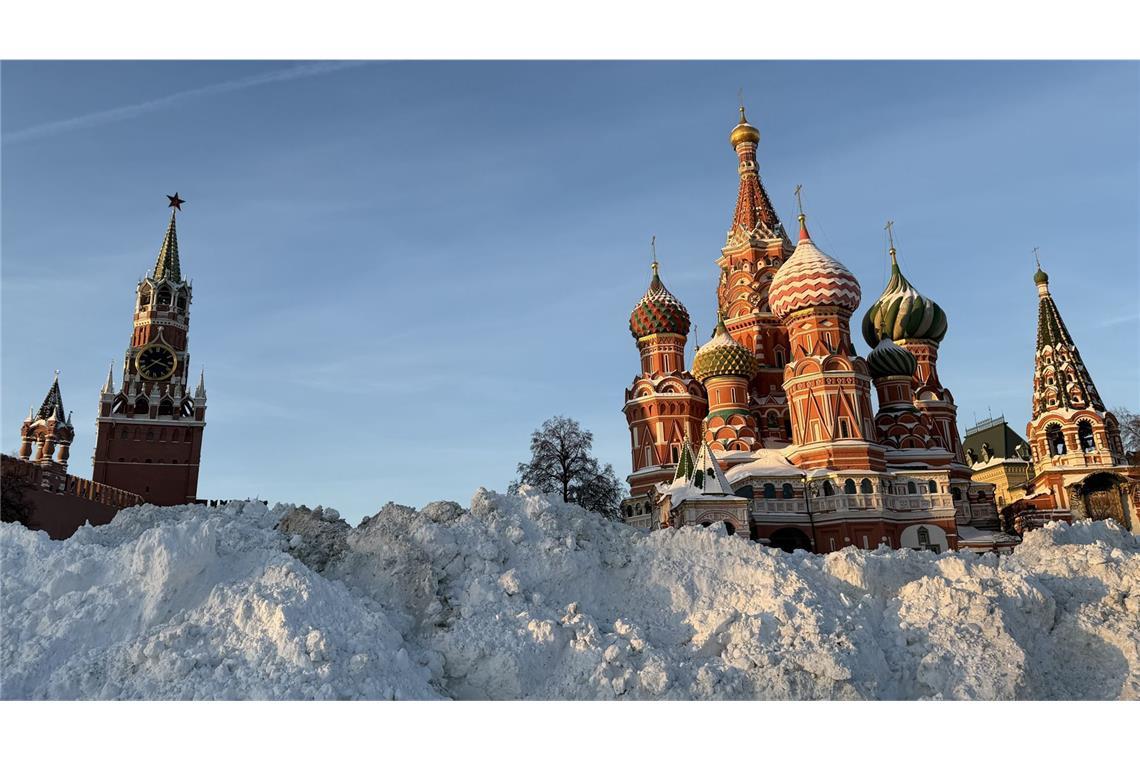 Der Spasski-Turm des Kreml (links) und die Basilius-Kathedrale (rechts) auf dem Roten Platz erstrahlen in der Nachmittagssonne hinter einem aufgeschütteten Berg von Schnee.