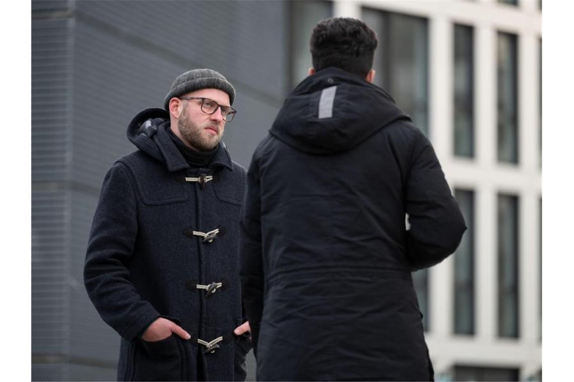 Der Streetworker Simon Fregin unterhält sich auf dem Mailänder Platz mit einem jungen Mann. Foto: Marijan Murat/dpa/archivbild