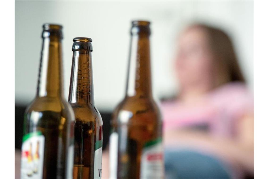 Süchtige Eltern: Aufwachsen in einer Extremsituation „Der Suchtkranke kreist nur um sich selbst und hat die Kinder nicht im Blick“: Eine Frau hinter leeren Bierflaschen. Foto: Alexander Heinl/dpa