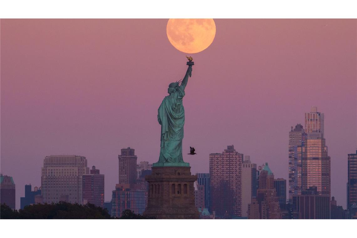 Der Supermond geht hinter der Freiheitsstatue in New York auf.