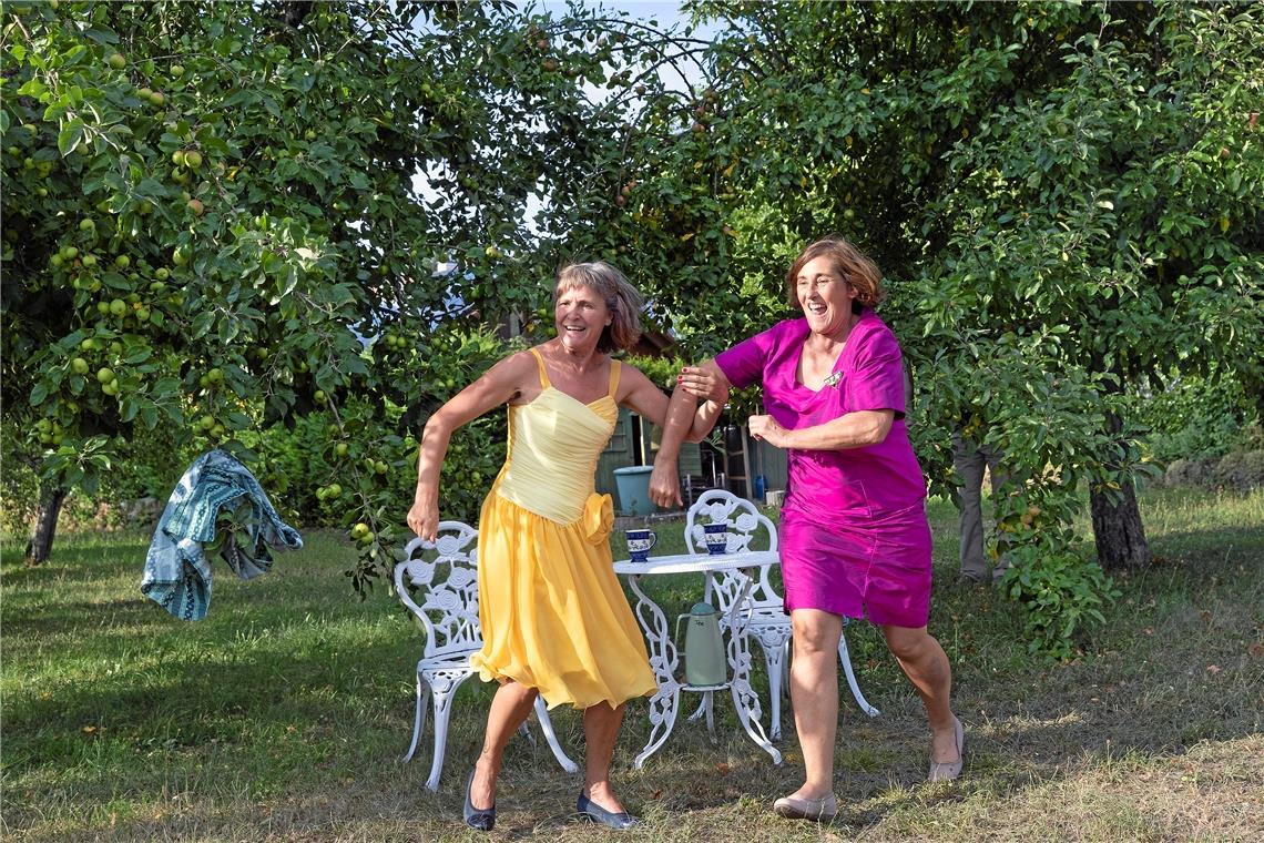 Der Überraschungsmoment kommt bei den Besuchern bestens an. Die beiden Frauen – Gerlinde Meyer (links) und Gabriele Gruber – die eben noch gemütlich unterm Apfelbaum Tee getrunken haben, reißen sich die Kittelschürzen vom Leib und stürmen in eleganten Kleidern davon. Foto: J. Fiedler
