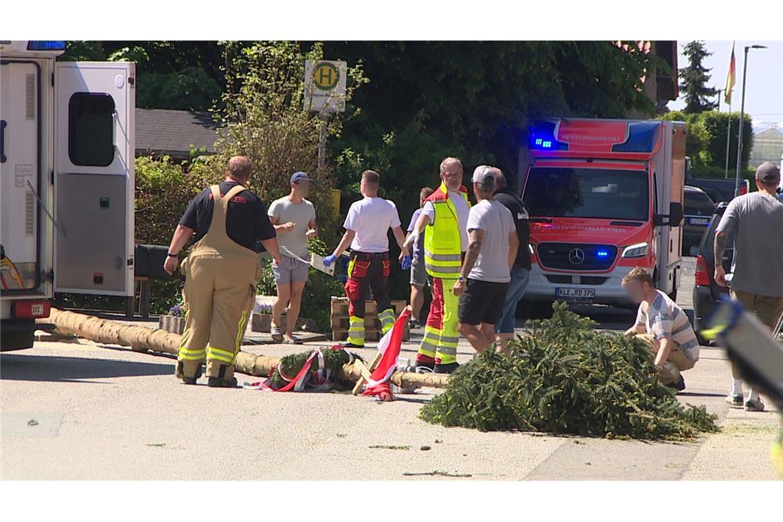 Der umgestürzte Maibaum liegt auf der Straße vor einem Einsatzwagen der Feuerwehr.