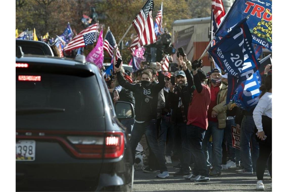Der US-Präsident Trump fährt in einer Autokolonne an einer Gruppe von Anhängern vorbei, die zu dessen Unterstützung und gegen angeblich gefälschte Wahlergebnisse in der Nähe des Weißen Hauses demonstrieren. Foto: Evan Vucci/AP/dpa